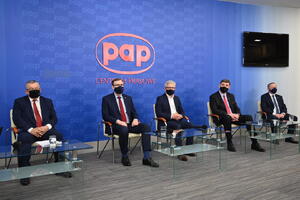 Pięciu mężczyzn w garniturach siedz na scenie podczas debaty