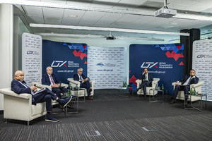 Uczestnicy konferencji siedzą na fotelach za nimi ścianki z logo UTK