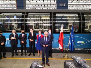 dr inż. Ignacy Góra, Prezes Urzędu Transportu Kolejowego podczas przemówienia na peronie za plecami pociąg Connecting Europe Express po prawej stronie flagi Polski oraz Unii Europejskiej