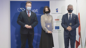 Po lewej stronie Minister Andrzej Bittel  po prawej Prezes UTK trzymający teczkę z podpisaną umową na dofinansowanie