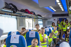 Wnętrze wagonu PKP Intercity w a nim dzieci ubrane w jasno żółte kamizelki podczas konferencji prasowej Kolejowego ABC II