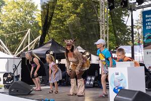 Na scenie znajdują się dzieci oraz DJ Miki, czyli Zuzanna Żyrafa. Dzieci oraz DJ Miki kucają łapiąc się za kolana Dj Miki ubrana jest w strój żyrafy