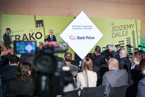 Zdjęcie z tyłu sali na zdjęciu widoczna publiczność zgromadzona na sali. Na scenie dr inż. Ignacy Góra, Prezes UTK który przemawia do zgromadzonych osób.